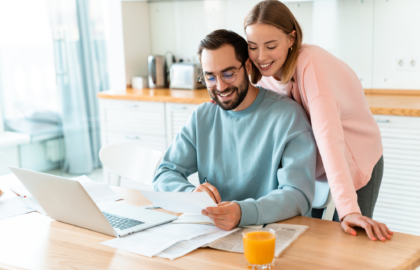 A couple looking at their laptop on the kitchen bench, exploring the tax benefits of investment properties.