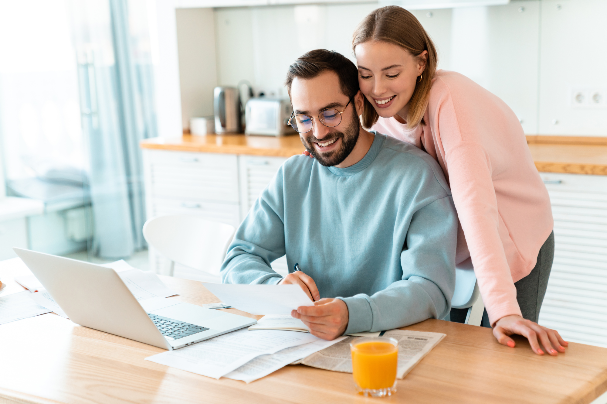 A couple looking at their laptop on the kitchen bench, exploring the tax benefits of investment properties.